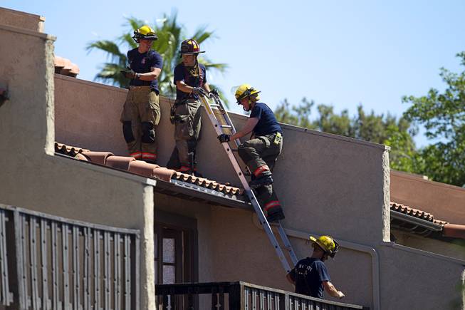 Firefighters inspect a roof after a two-alarm apartment fire near Tropicana and Eastern Avenue, March 30, 2015.