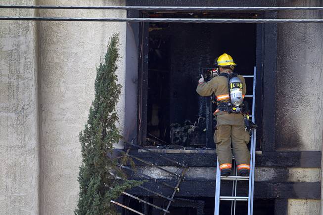 A firefighter inspects the second floor of an apartment after a two-alarm fire near Tropicana and Eastern avenues Monday, March 30, 2015.