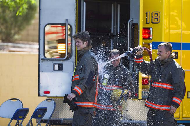 A firefighter is hosed down after fighting a two-alarm apartment fire near Tropicana and Eastern avenues Monday, March 30, 2015.