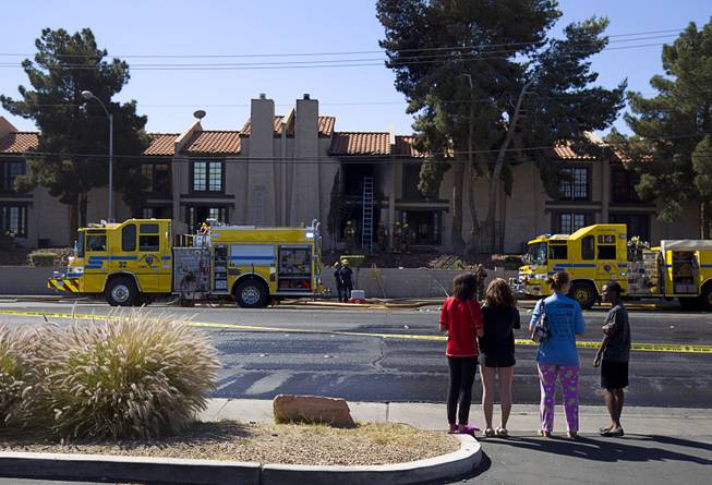 Bystanders watch firefighters after a two-alarm apartment fire near Tropicana and Eastern avenues Monday, March 30, 2015.