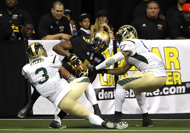 Jomo Wilson (15), center, of the Las Vegas Outlaws is tackled by David Hyland (3) and Ken Fontenette (5) of the San Jose SaberCats during the Outlaws' inaugural game against the San Jose SaberCats at the Thomas & Mack Center Monday, March 30, 2015.