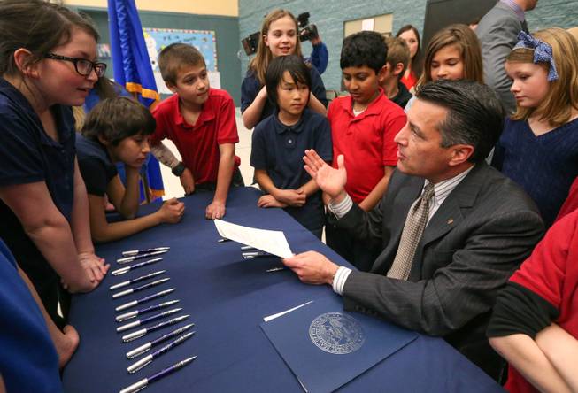 Nevada Gov. Brian Sandoval talks with a group of Carson City fifth-graders after signing into law an emergency bill extending bonds for school construction at a brief ceremony in Carson City, Nev., on Wednesday, March 4, 2015. More than a dozen lawmakers joined Sandoval for the signing of the bill which had bipartisan support in both houses. 