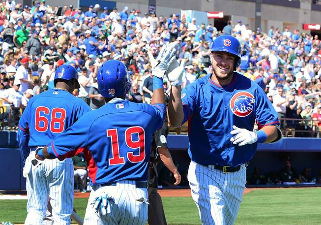 In this photo provided by the Las Vegas News Bureau, Chicago Cubs' Kris Bryant, right, celebrates with a teammate after hitting a home run in the third inning of a spring training baseball game against the Oakland Athletics, Saturday, March 14, 2015, in Las Vegas. 