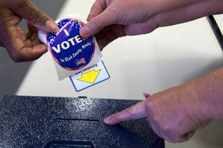 A voter deposits her voting card into a ballot box during voting at Becker Middle School in Summerlin Tuesday, April 7, 2015.