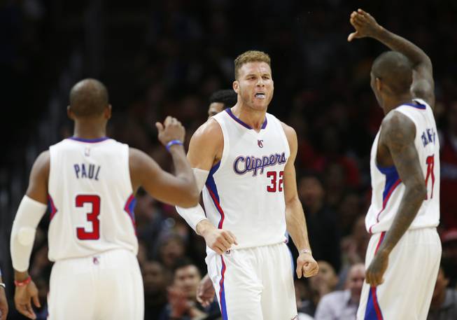 The Los Angeles Clippers' Blake Griffin, center, celebrates with teammates Chris Paul, left, and Jamal Crawford after scoring while being fouled by Denver Nuggets' Kenneth Faried during the second half of an NBA basketball game April 13, 2015, in Los Angeles. The Clippers won 110-103. 