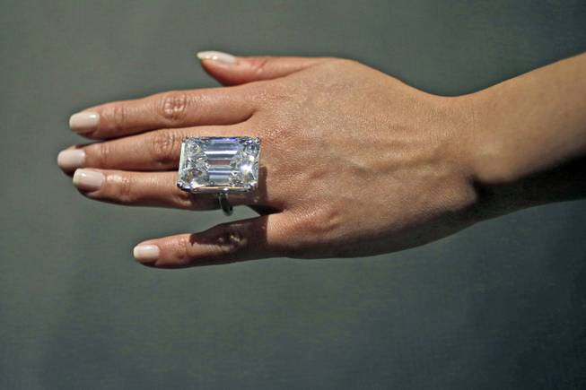 A Sotheby's employee models a 100-carat emerald-cut diamond, Friday, April 17, 2015, in New York. The "perfect" 100-carat diamond in a classic emerald cut is going on the auction block, where it could fetch between $19 million to $25 million. Sotheby's will offer the white diamond on April 21, in New York. 