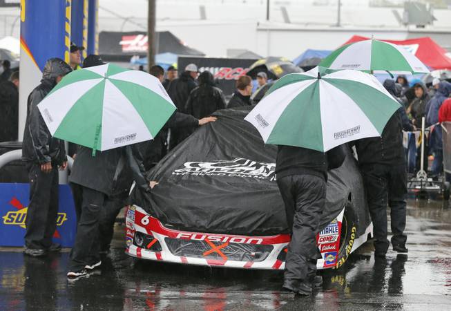 The crew for Trevor Bayne pushes his car to the inspection station as rain falls at Richmond International Raceway in Richmond, Va., Saturday, April 25, 2015. The NASCAR Sprint Cup series races was postponed until Sunday. 