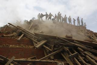 Volunteers help remove debris of a building that collapsed at Durbar Square, after an earthquake in Kathmandu, Nepal, Saturday, April 25, 2015. A strong magnitude-7.9 earthquake shook Nepal's capital and the densely populated Kathmandu Valley before noon Saturday, causing extensive damage with toppled walls and collapsed buildings, officials said. (AP Photo/ Niranjan Shrestha)