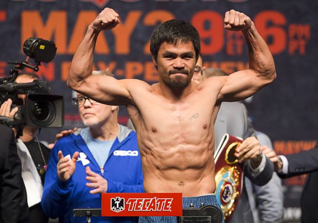 WBO welterweight champion Manny Pacquiao of the Philippines poses on the scale during an official weigh-in at the MGM Grand Garden Arena Friday, May 1, 2015. Pacquiao will face undefeated WBC/WBA welterweight champion Floyd Mayweather Jr.  in a welterweight unification bout at the arena on Saturday.