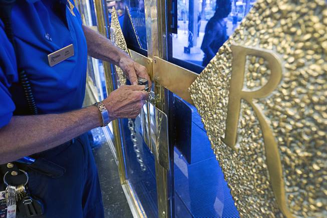 12 noon - A security officer puts chains on the front doors of the Riviera Monday, May 4, 2015. The 60-year-old Riviera, which was the Las Vegas Strip's first high-rise property, will be imploded to make way for a $2.3 billion convention center business district facility.