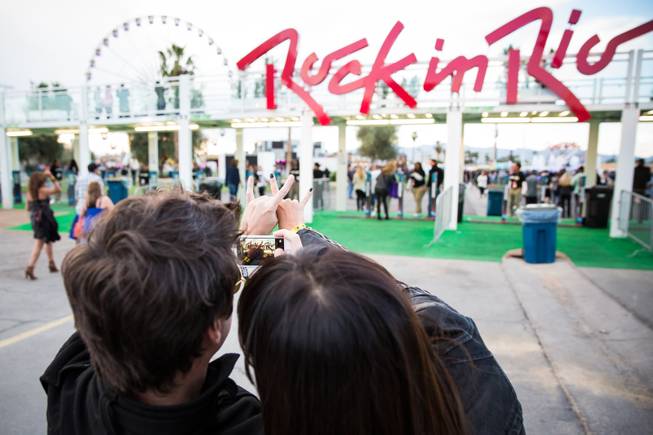 A couple takes a photo of their hands  in front of the entrance to Rock in Rio, Las Vegas, Friday, May 8, 2015.