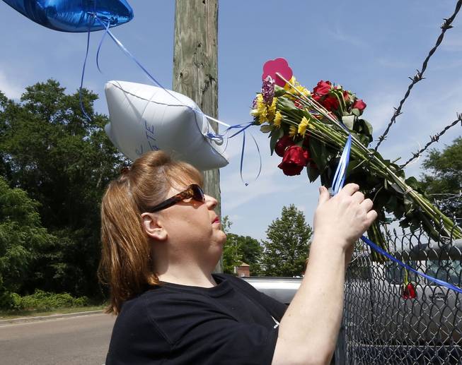 Donna Nelson of Petal, Miss., pays her respects at a makeshift memorial, near the site where two Mississippi police officers were killed, Sunday, May 10, 2015, in Hattiesburg, Miss.