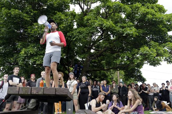 Rafael Ruiz speaks through a megaphone to a crowd gathered at a park to protest a police shooting in Olympia, Wash., on Thursday, May 21, 2015. Police say that two stepbrothers suspected of trying to steal beer from a grocery store were not armed with guns when they were shot by a police officer who confronted them. 