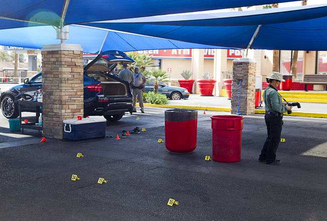 A crime scene analyst takes photos as Metro Police investigate a shooting at Arville Street and Flamingo Road Sunday, May 24, 2015. Four people were reported shot at a Terrible Herbst gas station and car wash in what is believed to be an attempted robbery of victims in a BMW outside of the gas station.