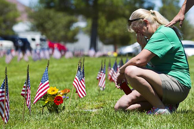 Alyson Darby of Las Vegas tends to her parent's graves on Memorial Day at the Southern Nevada Veterans Memorial Cemetery in Boulder City Monday, May 24, 2015. Her father Joseph Darby served in the army during World War II, she said.