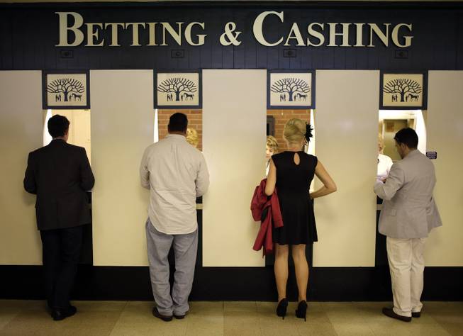 In this June 8, 2013, file photo, people stand at a betting and cashing window at Belmont Park in Elmont, N.Y., before the Belmont Stakes. 