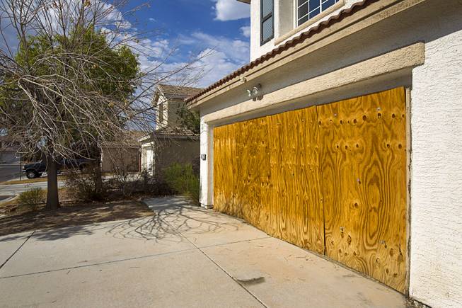 The garage door is boarded at a foreclosed home in a neighborhood near Tenaya Way and Russell Road Thursday, June 25, 2015.