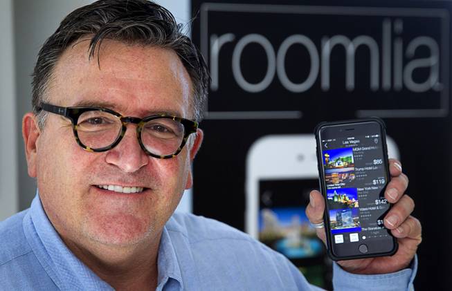 Jim Ferguson, co-founder of Roomlia, poses with his iPhone in the company's offices Thursday, June 25, 2015. Roomlia is a mobile hotel booking app for iPhone and Android devices.