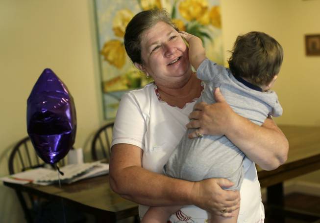 In this Monday, June 22, 2015, photo, Jennifer Greene, 58, holds her grandson while babysitting at her daughter's home in Delray Beach, Fla. Greene 58, had feared she would have to go without insurance if she lost her $547-a-month tax credit, but a Thursday, June 25, 2015, Supreme Court ruling validated federal health insurance subsidies for nearly 6.4 million Americans.