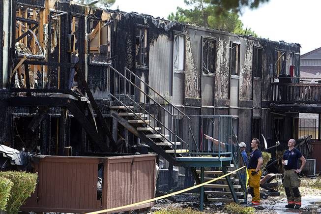 Firefighters survey the scene after an early morning three-alarm fire at the Sandpebble Village apartments at Arville Street and Sirius Avenue Sunday, June 28, 2015.