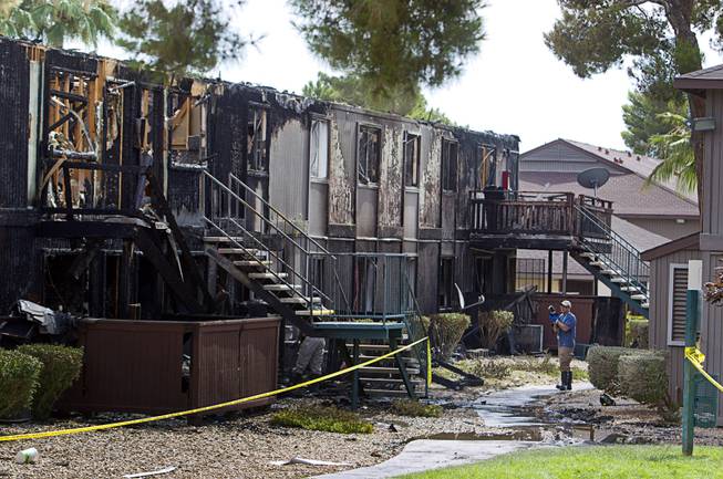 An inspector takes a photo after an early morning three-alarm fire at the Sandpebble Village apartments at Arville Street and Sirius Avenue Sunday, June 28, 2015.