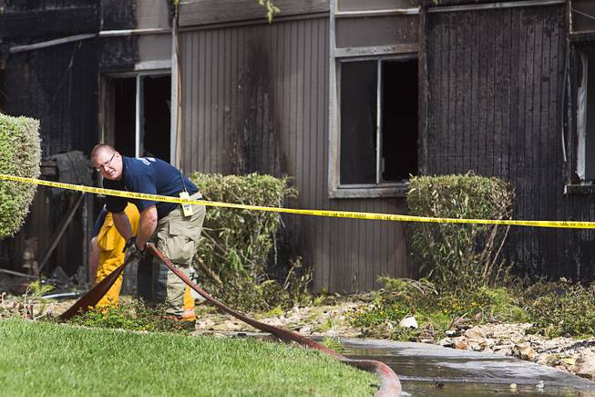 A firefighter breaks down a hose after an early morning three-alarm fire at the Sandpebble Village apartments at Arville Street and Sirius Avenue Sunday, June 28, 2015.