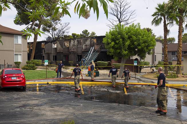 Firefighters break down equipment after an early morning three-alarm fire at the Sandpebble Village apartments at Arville Street and Sirius Avenue Sunday, June 28, 2015.