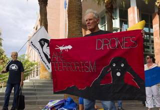 Anti-drone activists Barry Binks, left, of Sacramento, Calif. and Dennis DuVall, center, of Prescott, Ariz. protest in front of the Clark County Regional Justice Center in Las Vegas Tuesday, June 30, 2015. Many of the activists are facing misdemeanor charges in relation to a March 6, 2015 protest at Creech Air Force Base, about 45 miles northwest of Las Vegas.