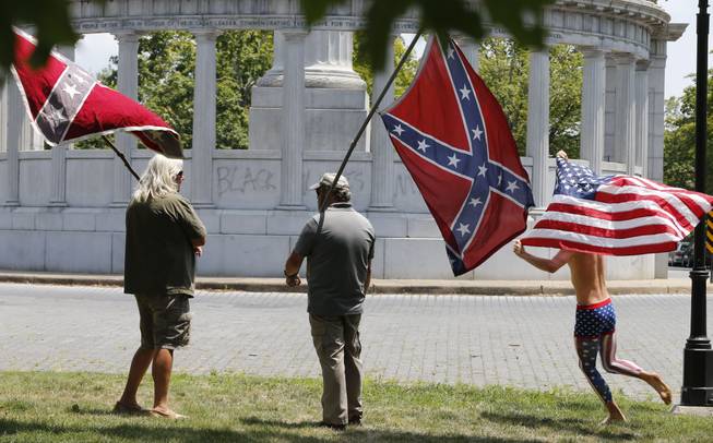 Members of the Virginia Flaggers demonstrate near the monument for Confederacy President Jefferson Davis in Richmond, Va., on Thursday as a runner carries an American flag. The monument was vandalized overnight, spray-painted with the phrase "Black Lives Matter." 