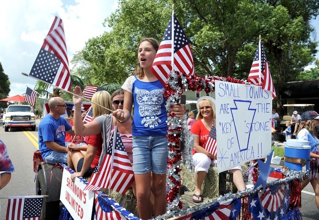 Ariana Kort waves a flag from the front of a float during the annual "Our Country Day" Parade in Keystone Heights, Fla.