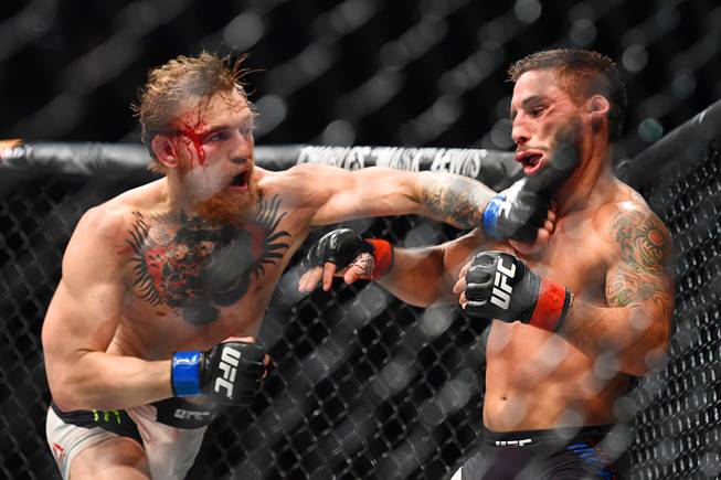 Conor McGregor sends Chad Mendes to the mat with a left to win by TKO in the third round of their featherweight title fight at UFC 189 Saturday, July 11, 2015 at the MGM Grand Garden Arena in Las Vegas, Nevada.