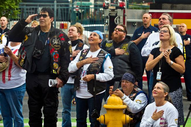 Attendees look on and say the Pledge of Allegiance as the 2015 Patriot Tour flag is raised during a stop at the Las Vegas City Hall with over 50 motorcycles along on Monday, July 20, 2015.