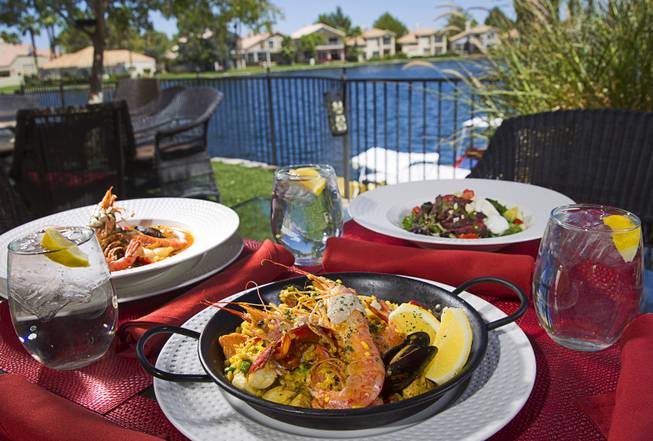 Paella Velazquez, center, Zarzuela, left, and Chimichurri Steak Cobb salad at Isabela's, Seafood, Tapas & Grill by Chef Brent, 2620 Regatta Dr., Sunday, July 26, 2015.