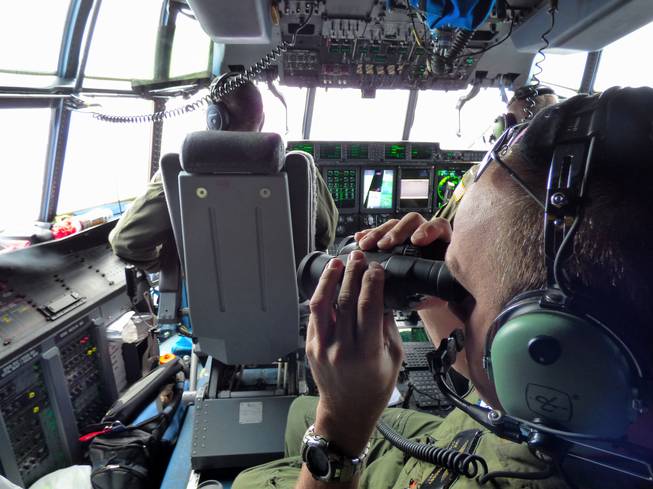 U.S. Coast Guard Petty Officer 1st Class Mike Crosby scans the Atlantic Ocean through binoculars from a Coast Guard HC-130J while searching for Florida teens Perry Cohen and Austin Stephanos on Tuesday, July 28, 2015.