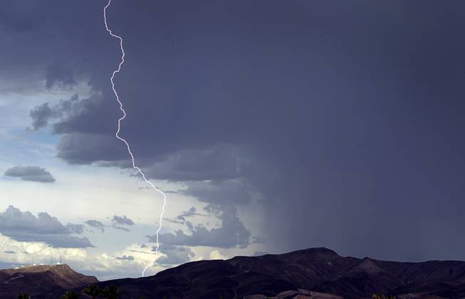 A bolt of lighting strikes behind the southern-valley mountains as a thunderstorm moves into Henderson Friday, July 31, 2015.