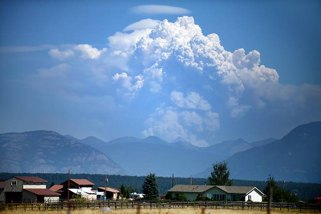 Plumes of smoke from the Thompson Fire in Glacier National Park rise into the sky, seen from Lost Creek Road and Farm-to-Market Road west of Kalispell, Mont., on Tuesday, on Aug. 11, 2015. The fire, burning heavy timber in the south-central part of Glacier National Park, has prompted some trail and campsite closures.