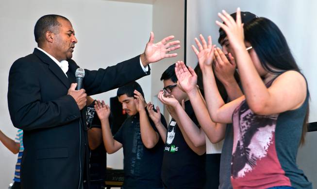 Pastor Victor Fuentes of the Ministerio Roca Solida Church prays over the youth in his congregation during services in their modified chapel within Roy Martin Middle School on Sunday, August 9, 2015.