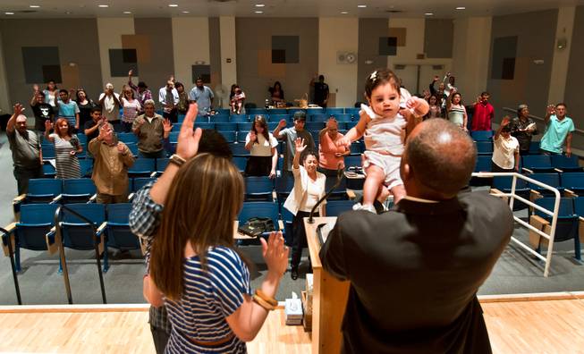 Pastor Victor Fuentes, from right, of the Ministerio Roca Solida Church blesses infant Paulette Alondra Reyes with her parents Wendy and Eric Reyes before their congregation during services in their modified chapel within Roy Martin Middle School on Sunday, August 9, 2015.