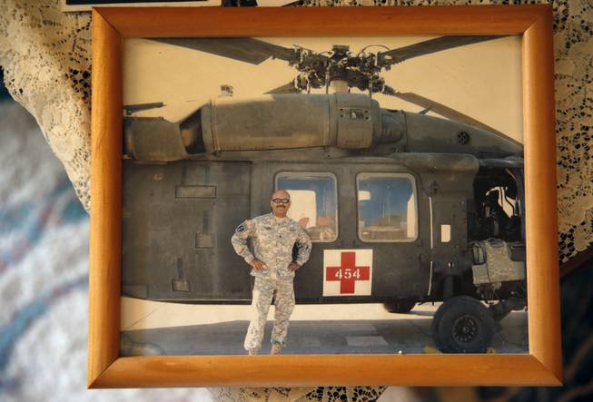A photograph of now-retired U.S. Army Sgt. 1st Class Marshall Powell standing with a U.S. Army Medevac helicopter in Iraq during his last tour to the country is seen March 17, 2015, at Powell's brother's house in Crescent, Okla. Powell, who served as a military nurse in Iraq and Afghanistan, was deeply haunted by his experiences, and nearly lost his own internal war with depression before finding meaningful help. 