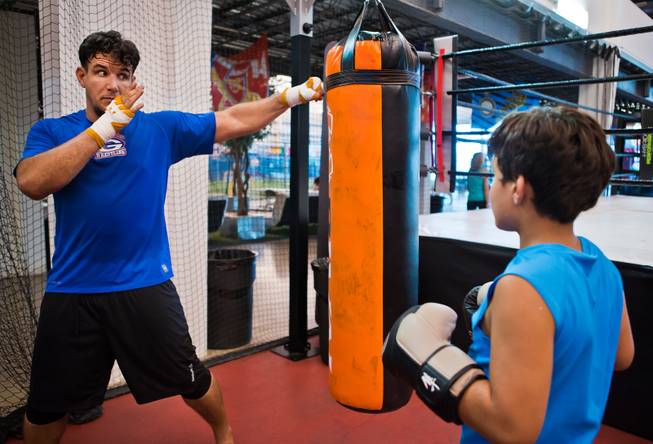 UFC fighter Frank Mir shows his his son Kage, 9, how to thrown a correct jab while hanging out with him and learning the sport at Hybrid Performance in preparation for his Labor Day weekend fight on Friday, August 14, 2015.