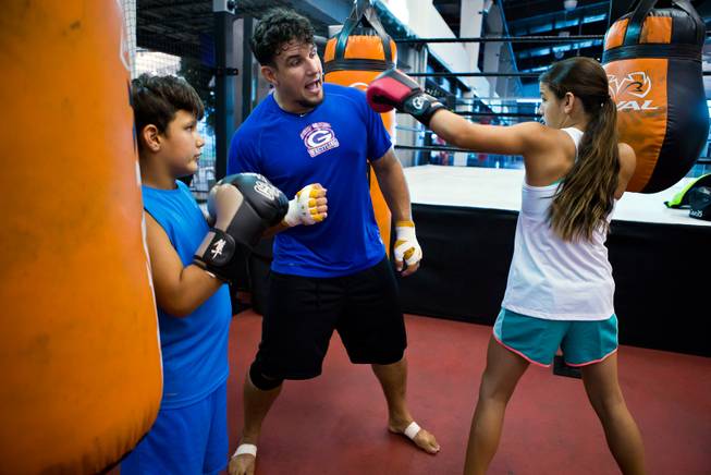 UFC fighter Frank Mir, center, avoids a jab from daughter Isabella, 12, as she and her brother Kage, 9, watch and learn the sport from their dad at Hybrid Performance on Friday, August 14, 2015.