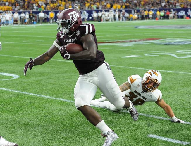 Texas A&M running back Tra Carson, left, eludes Arizona State defensive back Jordan Simone (38) on his way to a touchdown Saturday in Houston.
