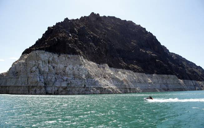 In this July 17, 2014, photo, recreational boaters ride by a bathtub ring that delineates the high water mark at Lake Mead.
