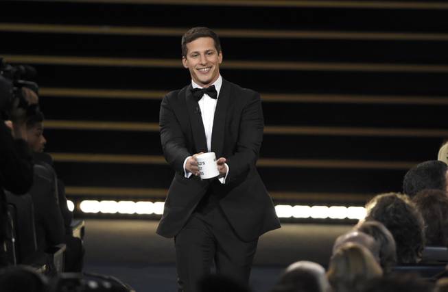 Host Andy Samberg prepares to present a coffee mug to Lorne Michaels at the 67th Primetime Emmy Awards on Sunday, Sept. 20, 2015, at Microsoft Theater in Los Angeles.