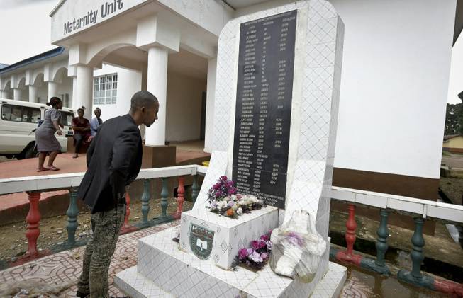 A man reads a monument with the names of health workers who died of Ebola Aug. 8, 2015, at the government hospital in Kenema, eastern Sierra Leone. An Associated Press investigation has found a toxic mix of avoidable problems faced by Ebola responders, including weak leadership, shoddy supplies and infighting, exacerbated a chaotic situation at a critical front in the battle against the virus.