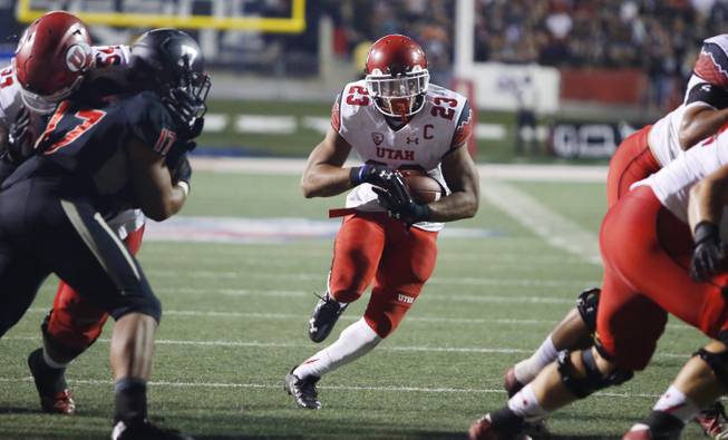 Utah's Devontae Booker runs through the line against Fresno State during the first half of an NCAA college football game in Fresno, Calif., Saturday, Sept. 19, 2015.