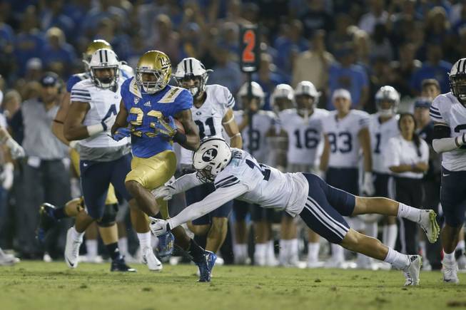 UCLA running back Nate Starks runs with the ball as BYU defensive back Kai Nacua dives for him during an NCAA college football game, Saturday, Sept. 19, 2015, in Pasadena, Calif. UCLA won 24-23.