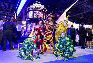Cirque du Soleil performers pose in front of Cirque du Soleil-themed slot machines in the Scientifc Games booth during the Global Gaming Expo (G2E) at the Sands Expo Center Tuesday, Sept. 29, 2015.