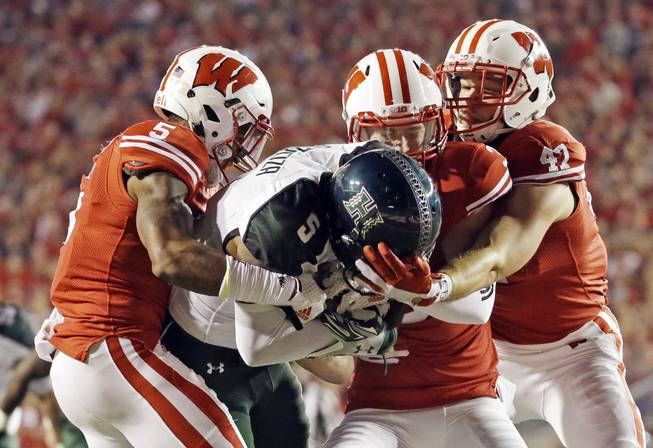 Wisconsin's Darius Hillary (5), Tanner McEvoy and Vince Biegel (47) stop Hawaii's Quinton Pedroza from scoring during the second half of an NCAA college football game Saturday, Sept. 26, 2015, in Madison, Wis.