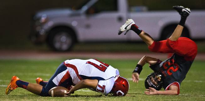 Coronado High School's punter Adolfo Sandoval, 77, loses a high snap for good as Las Vegas' Jacob Bowden, 22, rolls over the top of him causing a turn over during their football game on Friday, December 02, 2015.